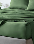 bambaw cozy bamboo bed sheets close up on a bed with fitted sheets and pillows in olive green colour
