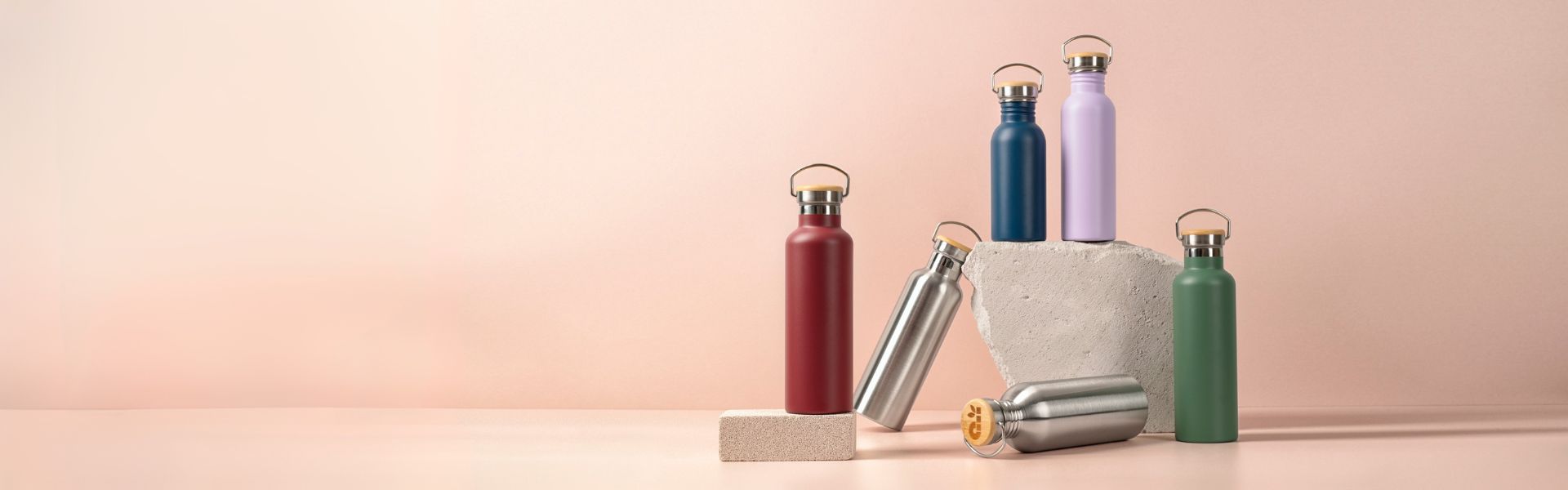 Set of colorful metal water bottles on a light pink background