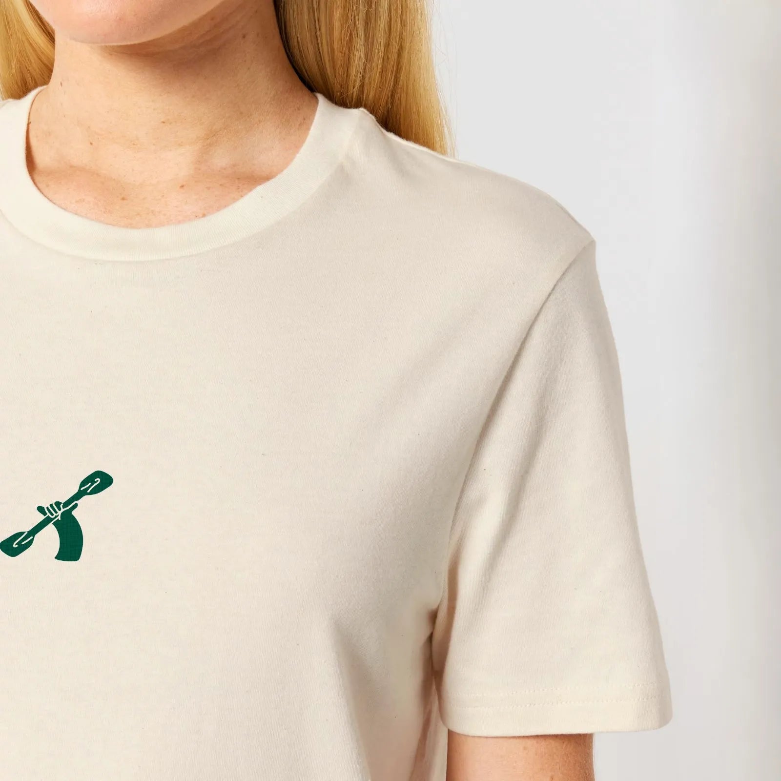 Natural raw white cotton t-shirt with a green City to Ocean logo worn by a woman on a white background
